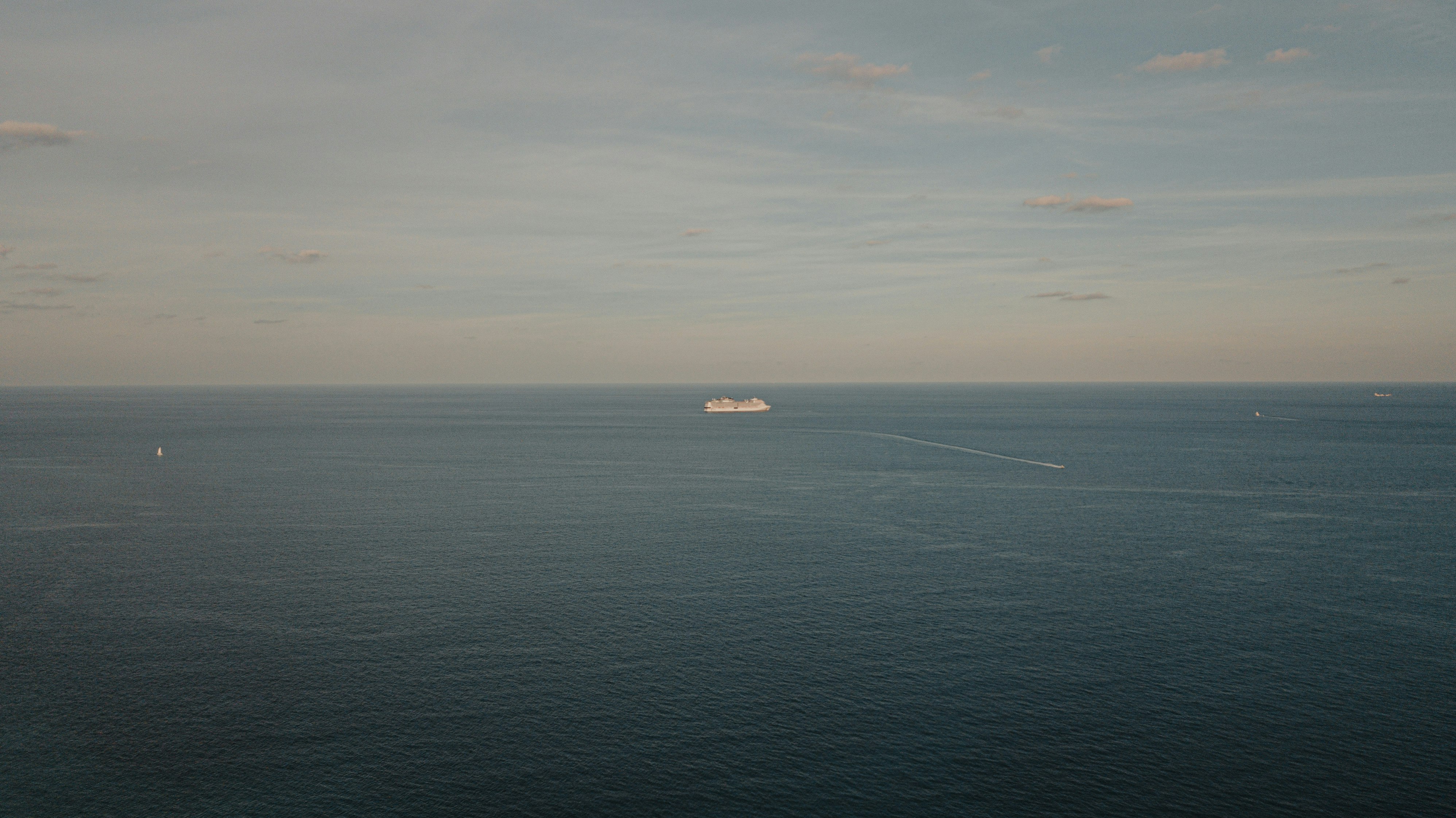 black boat on blue sea under white clouds during daytime